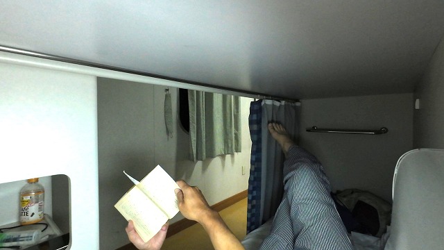 新日本海フェリーのツーリストAの室内で寝転んで小説を読んでいる男の画像