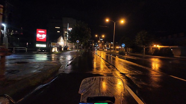 雨の小樽の街を夜間にバイクで走っている画像